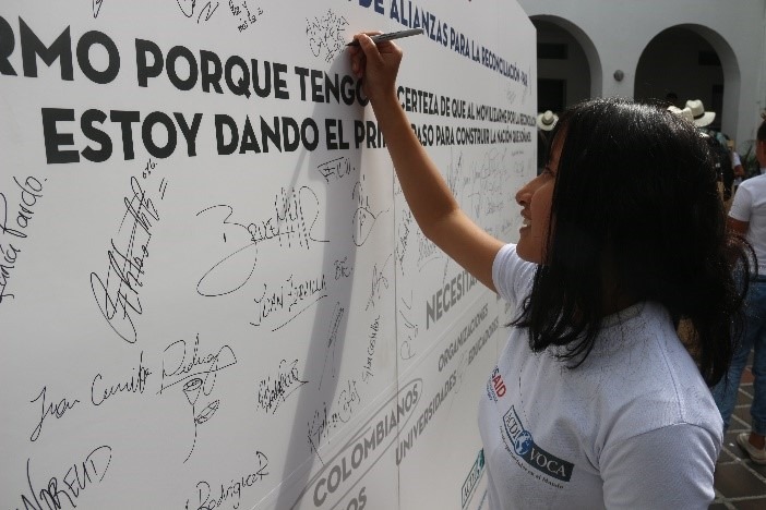 Florencia residents sign a poster signifying their commitment to reconciliation