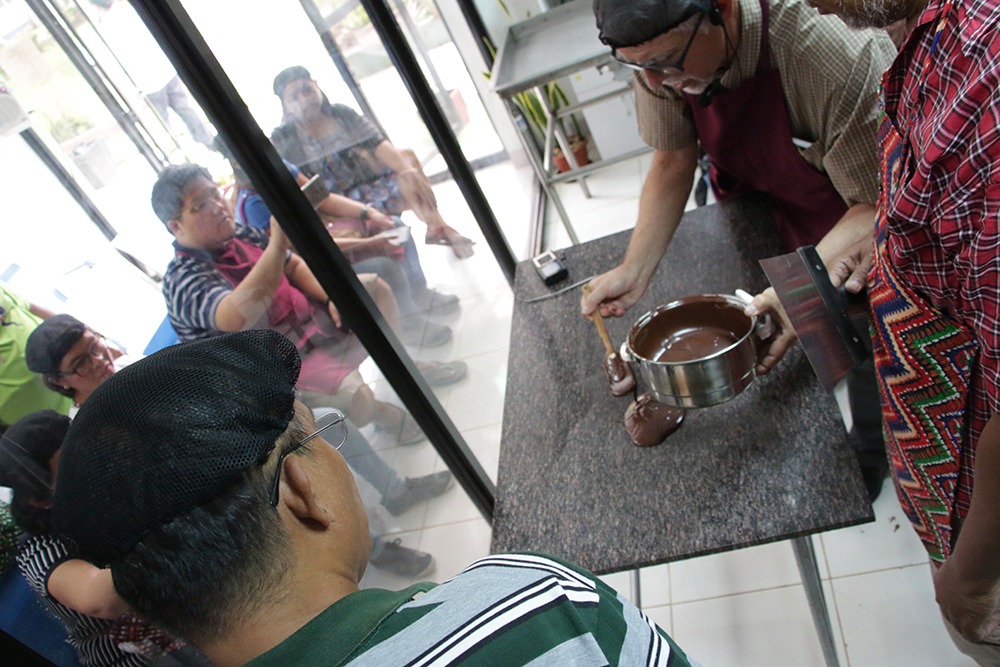 ACDI/VOCA MinPACT Workshop Pouring the chocolate on table in prep for tempering