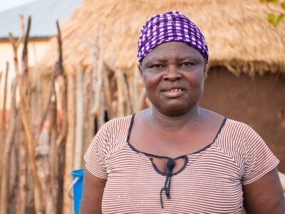 Woman smiling by thatched hut in Ghana