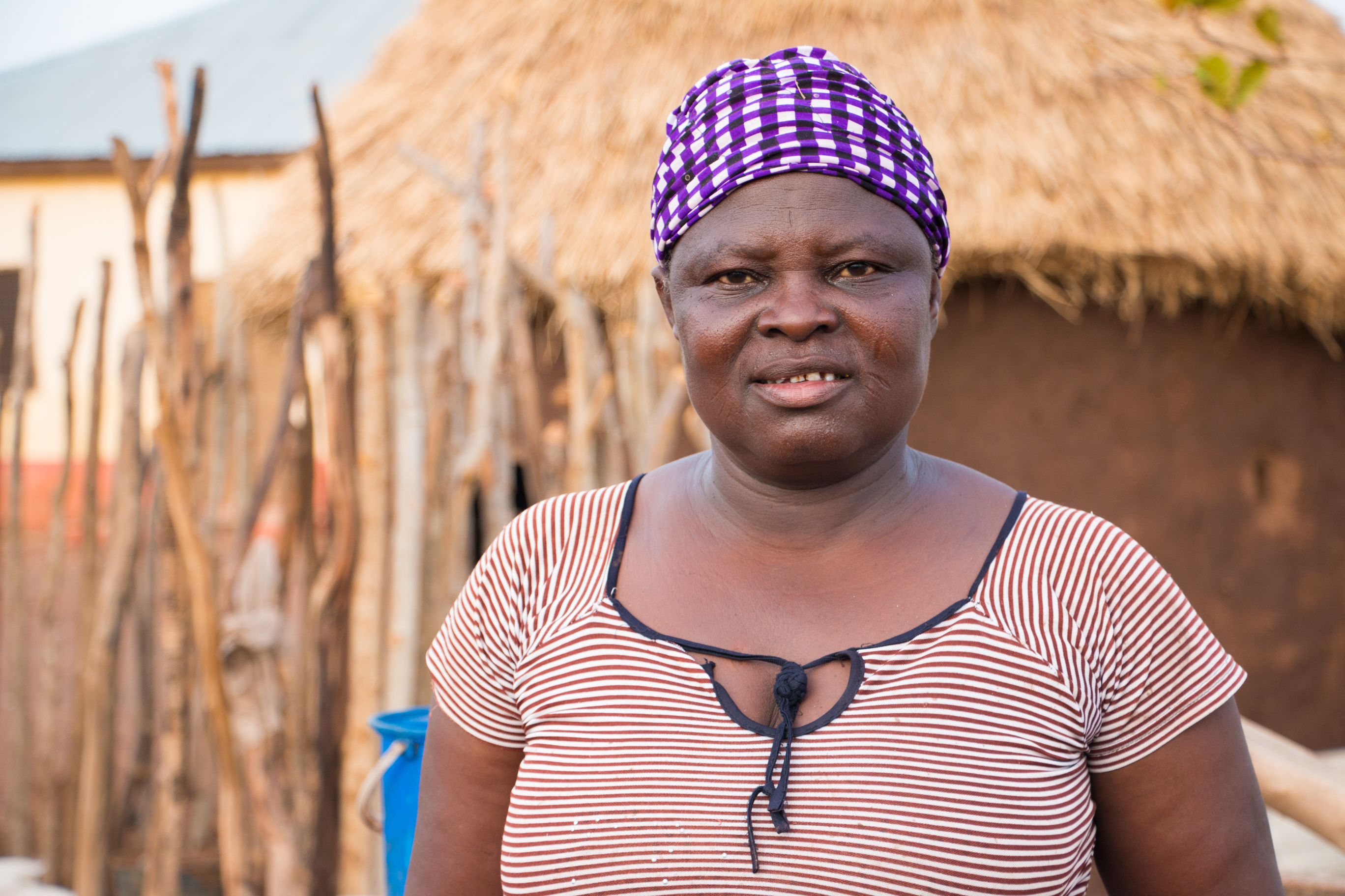 Woman smiling by thatched hut in Ghana